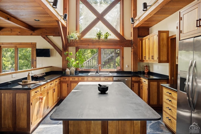 kitchen with beamed ceiling, a center island, stainless steel appliances, and a healthy amount of sunlight