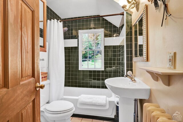 bathroom with radiator heating unit, lofted ceiling, tile patterned floors, shower / bath combination with curtain, and toilet