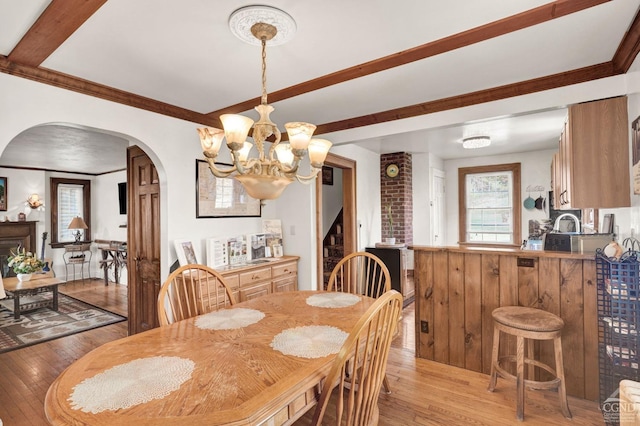 dining area featuring crown molding, light wood-type flooring, and a chandelier