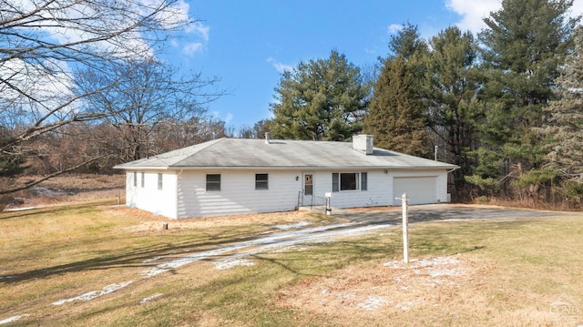 rear view of property featuring a garage and a yard