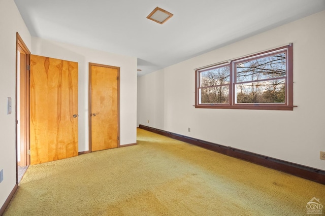 unfurnished bedroom featuring light colored carpet and multiple closets