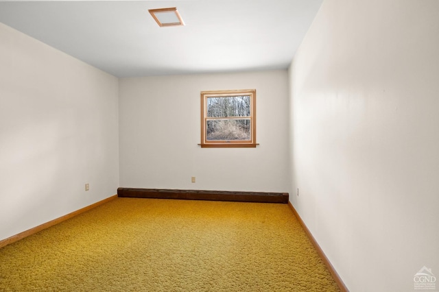 carpeted empty room featuring a baseboard heating unit