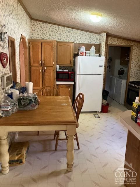 dining area featuring washer / dryer, a textured ceiling, vaulted ceiling, and ornamental molding