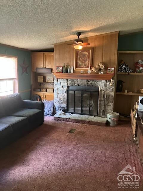 carpeted living room featuring a fireplace, a textured ceiling, and ceiling fan