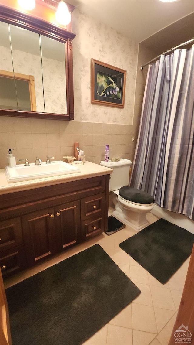 bathroom featuring a shower with shower curtain, vanity, tile walls, tile patterned flooring, and toilet