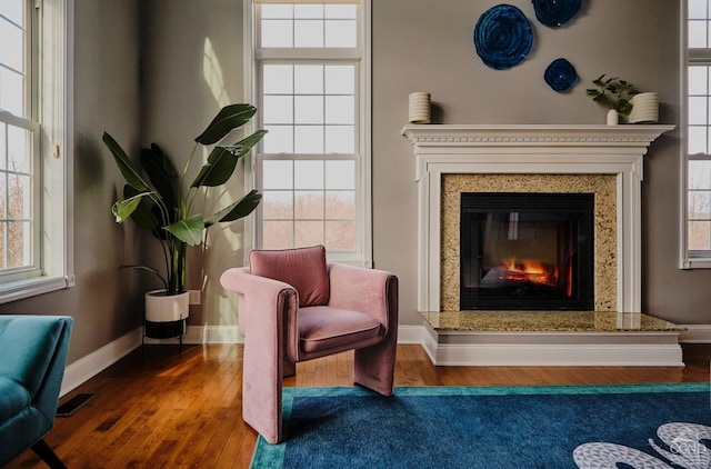 living area with plenty of natural light, a high end fireplace, and wood finished floors