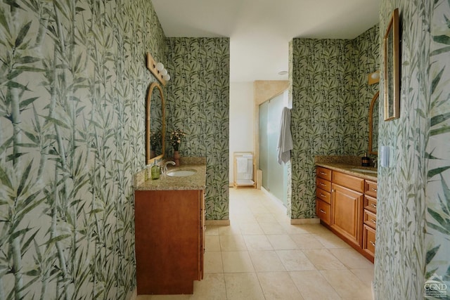 full bath with a sink, two vanities, and wallpapered walls