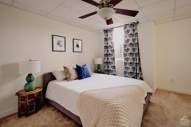 carpeted bedroom featuring baseboards, a ceiling fan, and a drop ceiling
