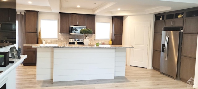 kitchen with light stone countertops, appliances with stainless steel finishes, light hardwood / wood-style floors, and a healthy amount of sunlight