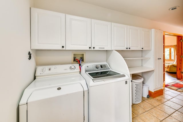 laundry room featuring washing machine and dryer, light tile patterned floors, and cabinets