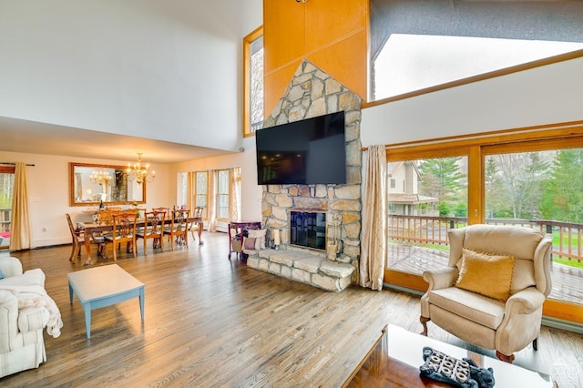 living room with a stone fireplace, a towering ceiling, and wood-type flooring