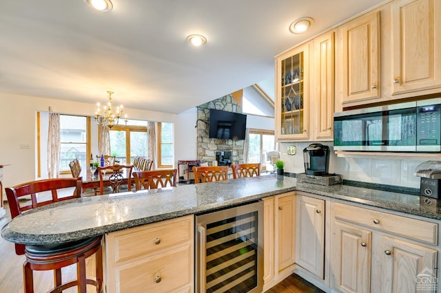 kitchen featuring hardwood / wood-style flooring, beverage cooler, a breakfast bar area, and dark stone countertops