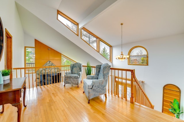 sitting room with beam ceiling, wood-type flooring, high vaulted ceiling, and a chandelier