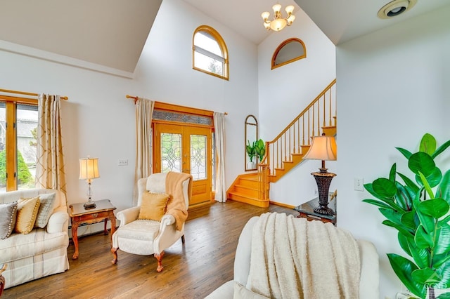 foyer with hardwood / wood-style floors, high vaulted ceiling, an inviting chandelier, and french doors