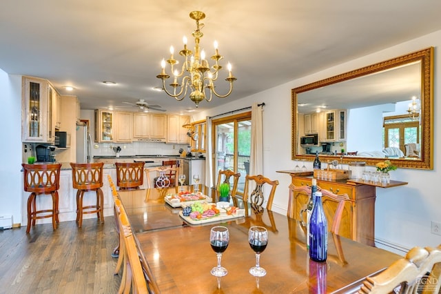 dining space featuring ceiling fan with notable chandelier, wood-type flooring, and baseboard heating