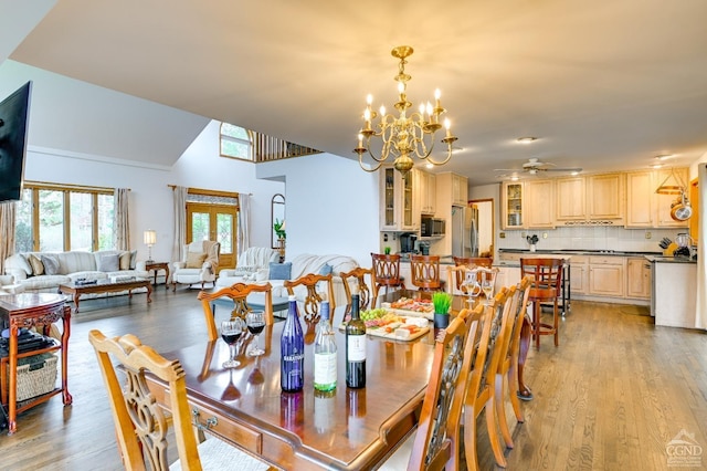 dining space with ceiling fan with notable chandelier and light hardwood / wood-style flooring