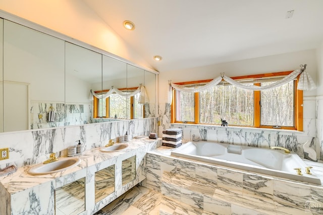 bathroom with vanity, tiled bath, and vaulted ceiling