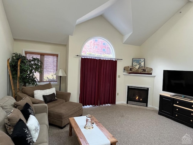 carpeted living room featuring high vaulted ceiling and a lit fireplace