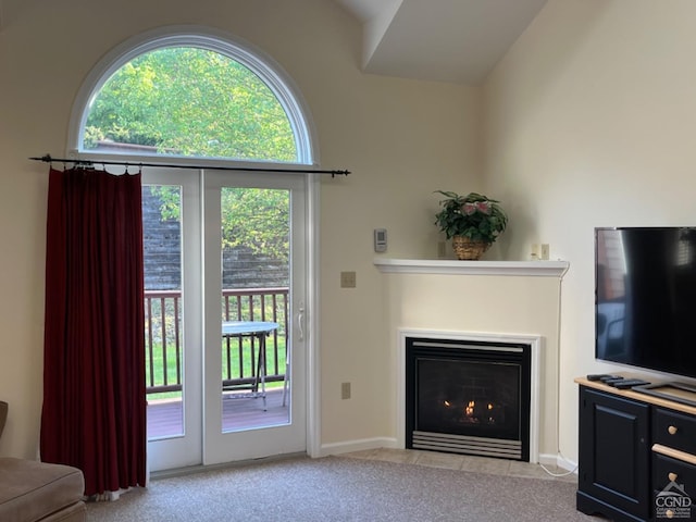 living room featuring a fireplace with flush hearth, carpet flooring, and vaulted ceiling