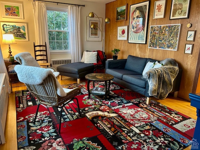 living room with radiator, wood-type flooring, and wooden walls