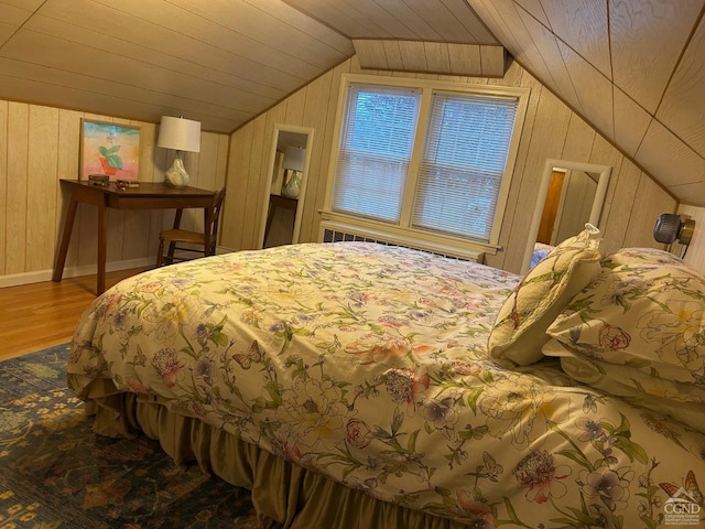 bedroom with hardwood / wood-style floors, wooden walls, and lofted ceiling