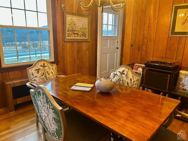 dining room with wooden walls, light hardwood / wood-style flooring, and a chandelier