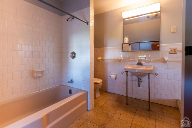 full bathroom featuring tiled shower / bath combo, sink, tile walls, tile patterned flooring, and toilet