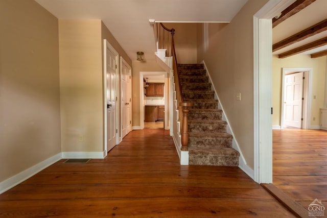 stairs with beam ceiling and hardwood / wood-style flooring