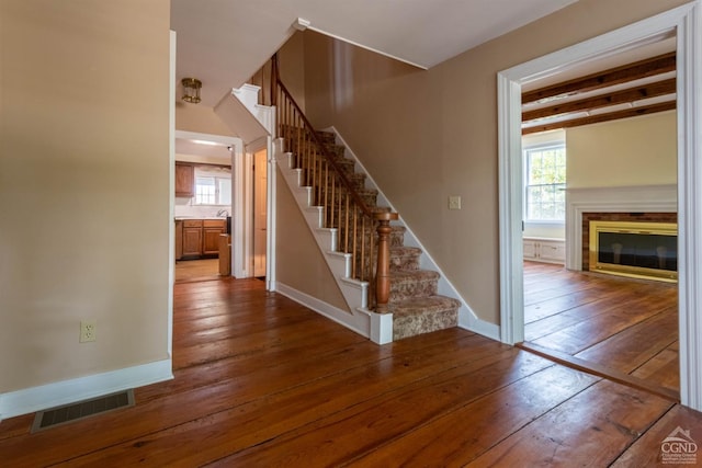 stairs with beamed ceiling and hardwood / wood-style flooring