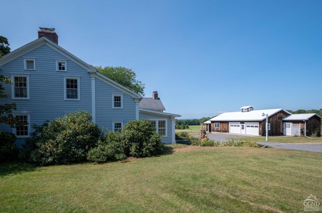 view of home's exterior with a yard, an outbuilding, and a garage