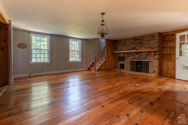 unfurnished living room with a brick fireplace and hardwood / wood-style flooring