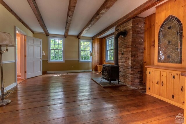 interior space with beam ceiling, a wood stove, and dark wood-type flooring