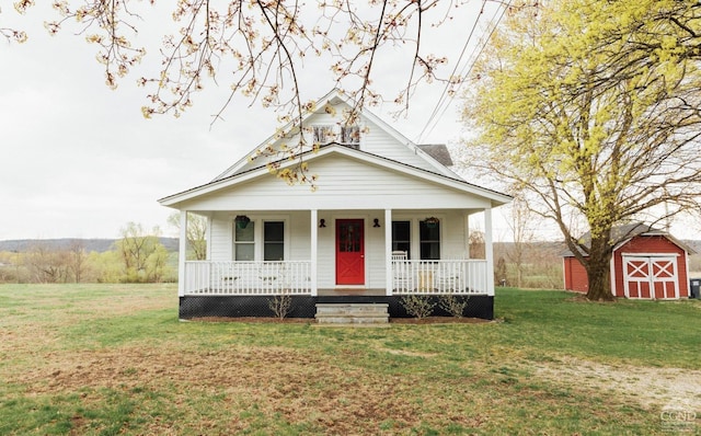bungalow featuring a porch, a shed, an outbuilding, and a front yard