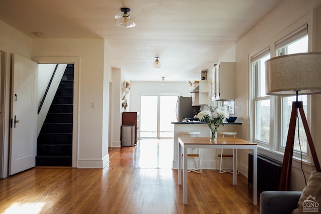 kitchen with open shelves, light wood-style floors, freestanding refrigerator, white cabinetry, and baseboards