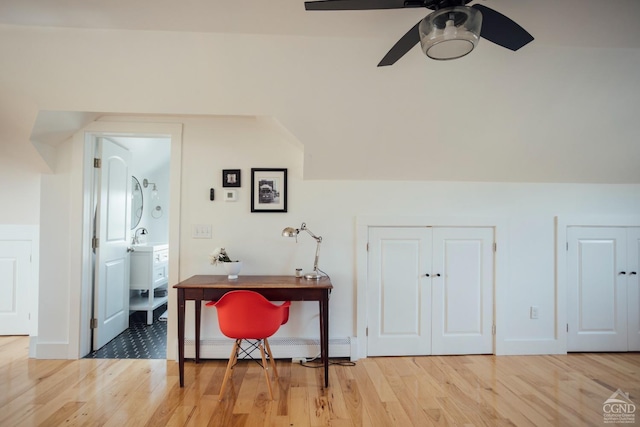 bonus room featuring a ceiling fan, a baseboard heating unit, a sink, and light wood-style floors
