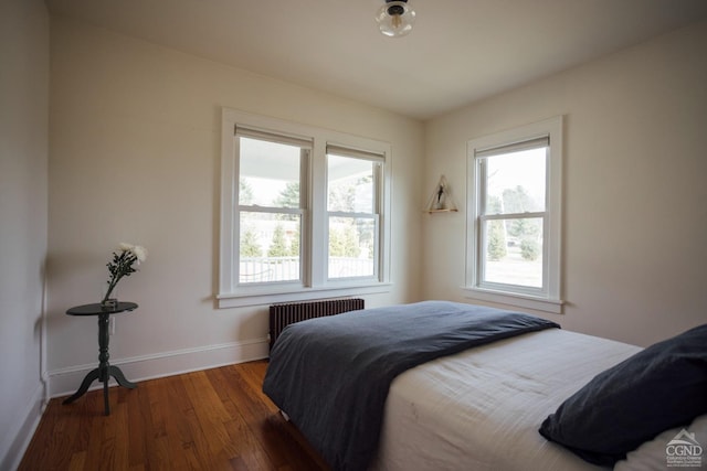 bedroom with baseboards, wood finished floors, and radiator