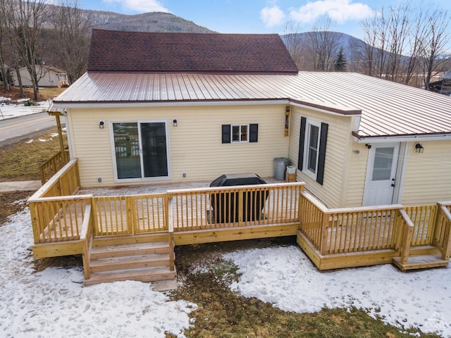 snow covered back of property featuring a deck with mountain view and metal roof