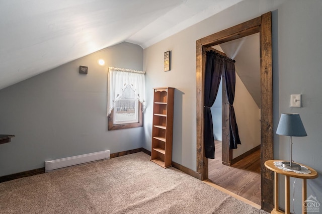 interior space with baseboard heating, carpet flooring, baseboards, and vaulted ceiling