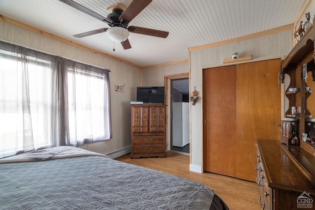 bedroom featuring a baseboard radiator, a closet, wood finished floors, and a ceiling fan