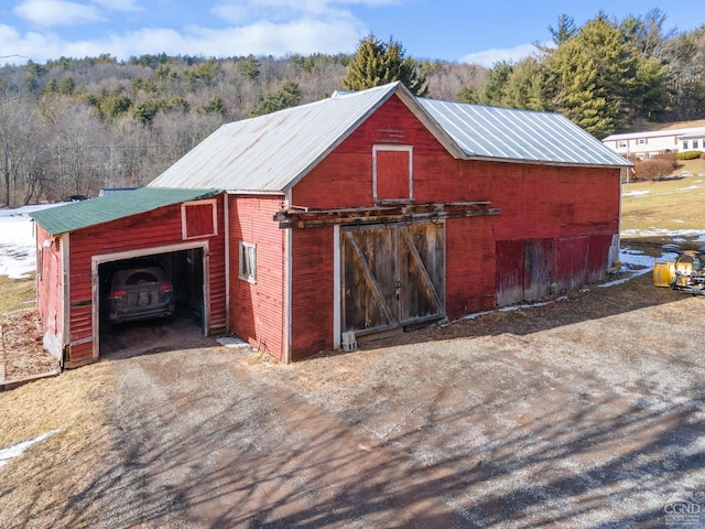 view of barn featuring a wooded view and driveway