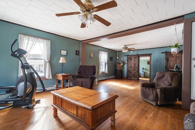 living room with a ceiling fan, a baseboard heating unit, a barn door, and hardwood / wood-style floors