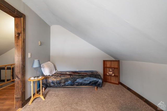 carpeted bedroom featuring vaulted ceiling and baseboards