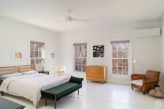 bedroom featuring a wall mounted air conditioner, ceiling fan, light hardwood / wood-style flooring, and multiple windows