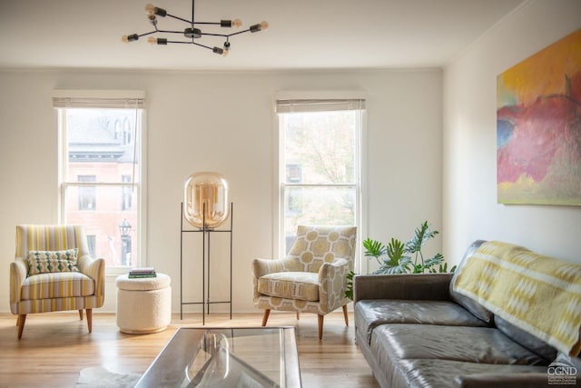 living area featuring crown molding, light hardwood / wood-style floors, and an inviting chandelier