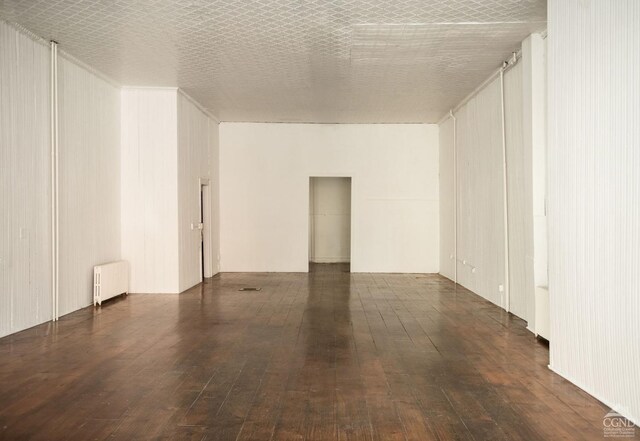 unfurnished room featuring radiator heating unit and dark wood-type flooring