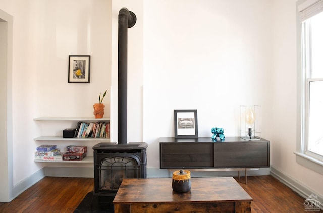 living area with dark hardwood / wood-style floors and a wood stove