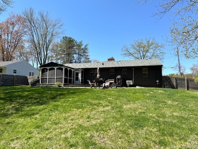 back of property featuring a chimney, a yard, a sunroom, and fence