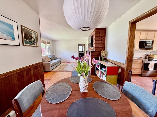 dining area featuring wooden walls, wainscoting, and light wood-style floors