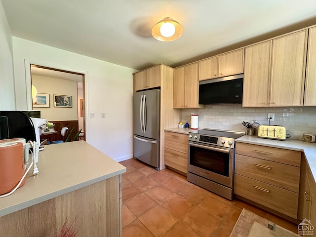 kitchen featuring tasteful backsplash, light tile patterned flooring, light brown cabinetry, light countertops, and appliances with stainless steel finishes