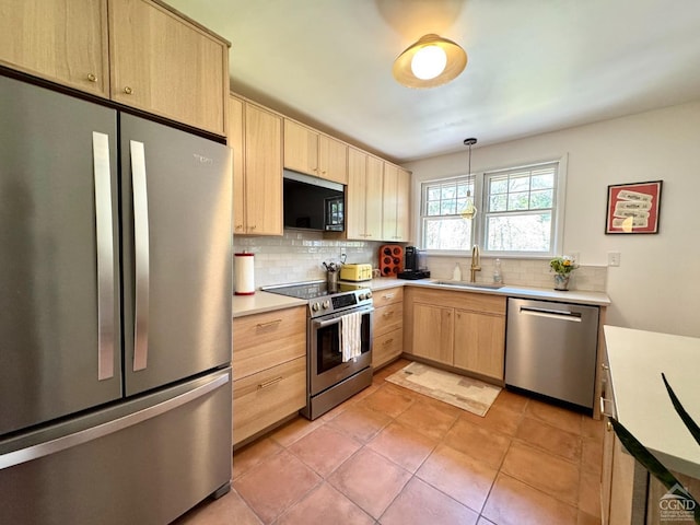 kitchen featuring light brown cabinets, a sink, light countertops, tasteful backsplash, and appliances with stainless steel finishes